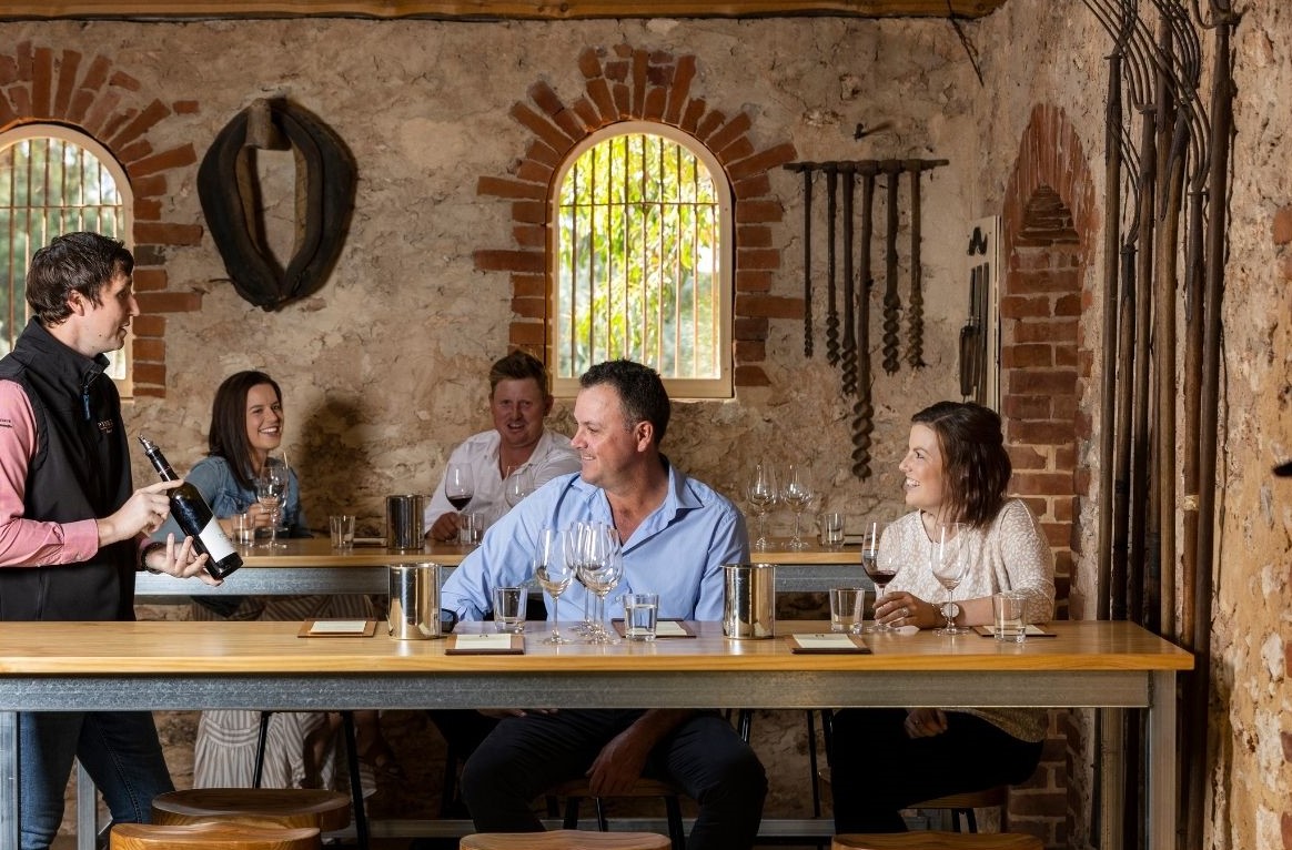 A man shows a bottle of wine to a group of people.